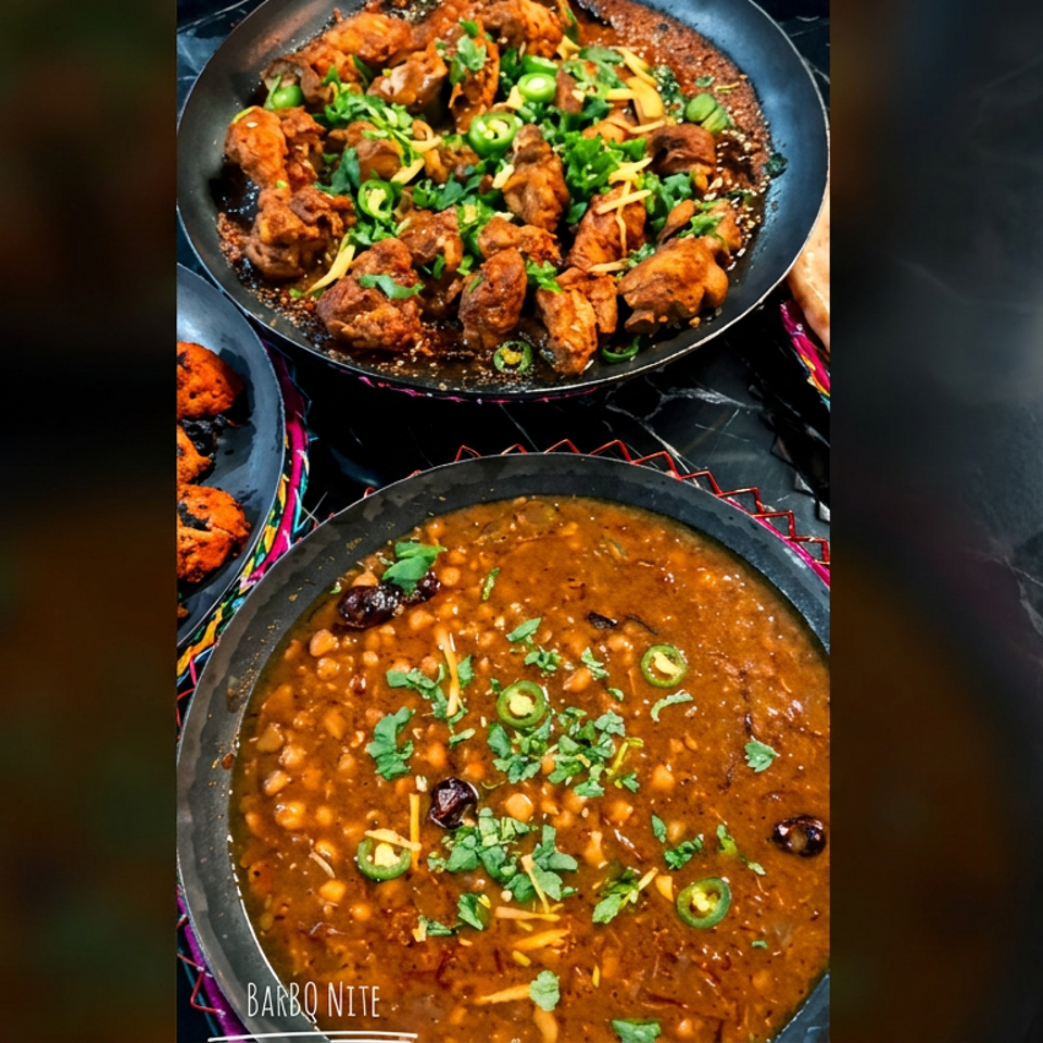 Indian dishes of spiced chicken and creamy lentils garnished with cilantro and green chilies in black serving pans.